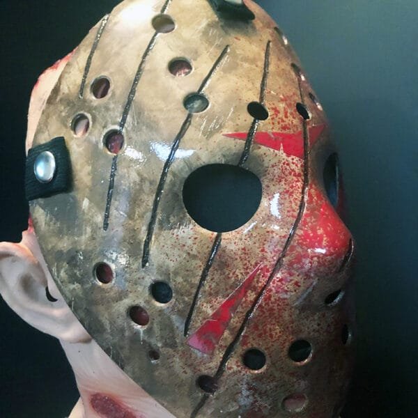 Angled close-up of the bloody Freddy vs Jason mask highlighting its weathered design, deep slashes, and vivid blood accents.