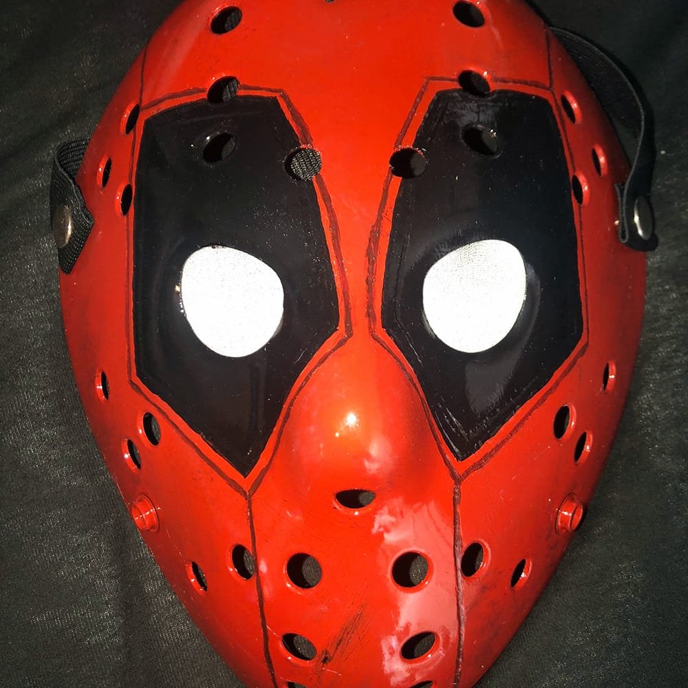 Front view of the Deadpool hockey mask with bold red and black paintwork.