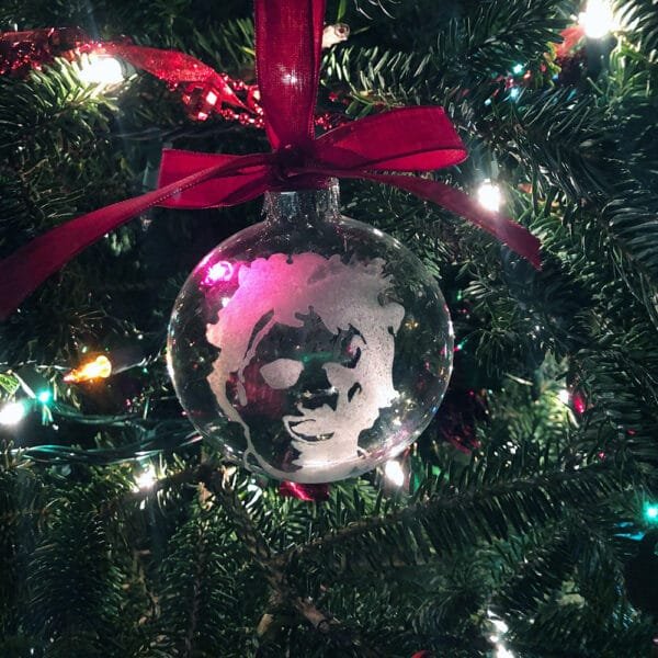 Horror movie ornament with Leatherface design, tied with a red satin bow.