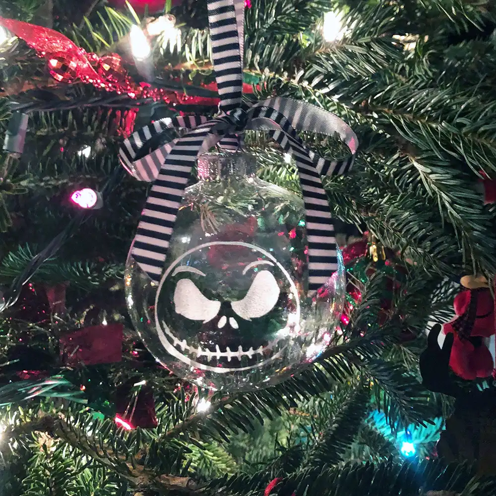 Nightmare Before Christmas ornaments, featuring Jack Skellington, hanging on a Christmas tree with striped ribbon.