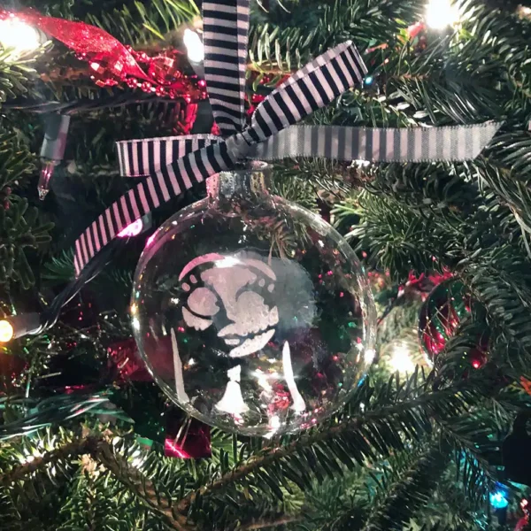 Sally glass ornament with striped ribbon on a Christmas tree.