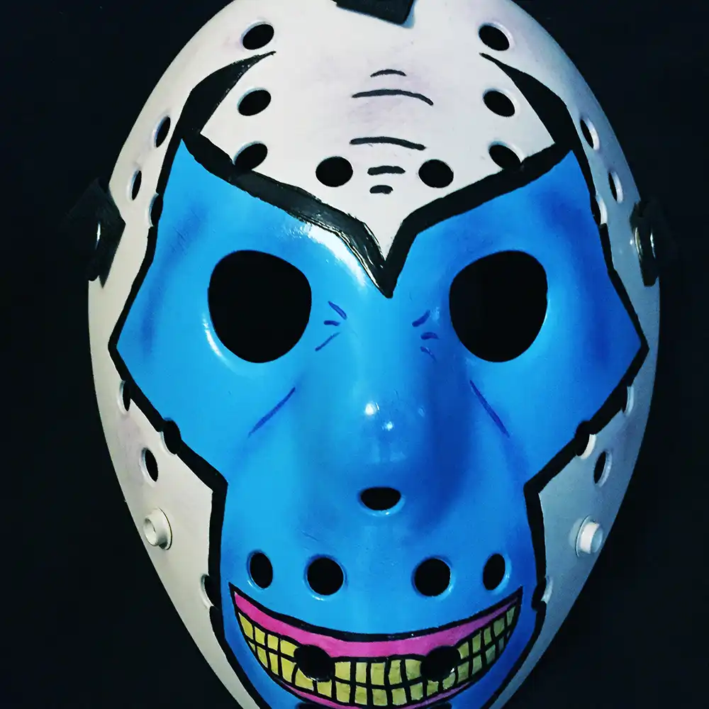 Hand-painted Violator Hockey Mask with blue face, yellow grin, and black outlines on white ABS plastic, set against a dark studio background.